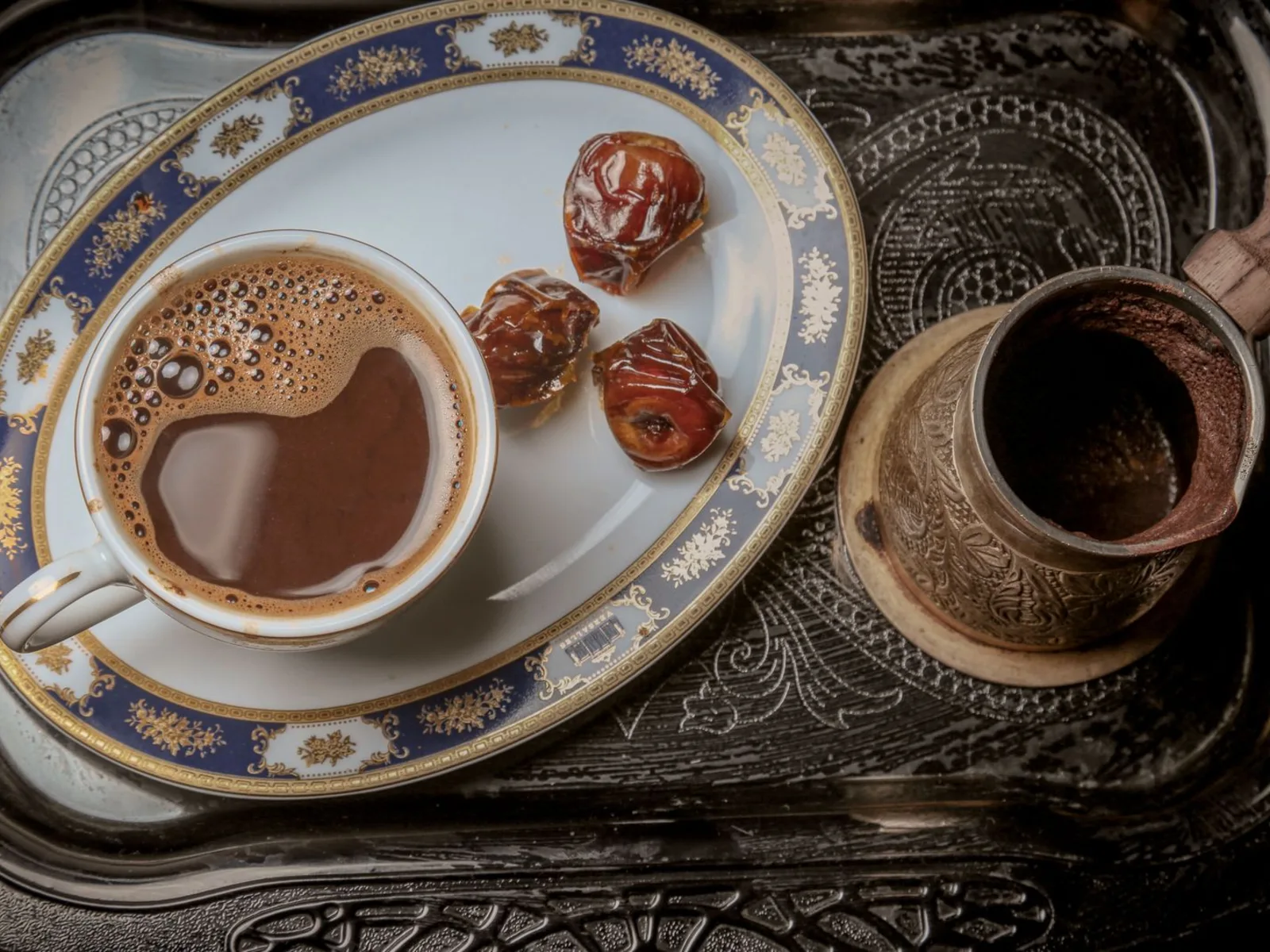Arabic coffee served with dates and a copper dallah on an engraved tray